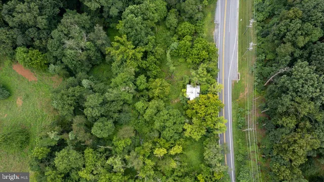 an aerial view of a residential houses with outdoor space and trees