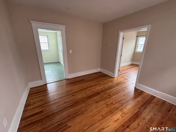 an empty room with wooden floor and mirror