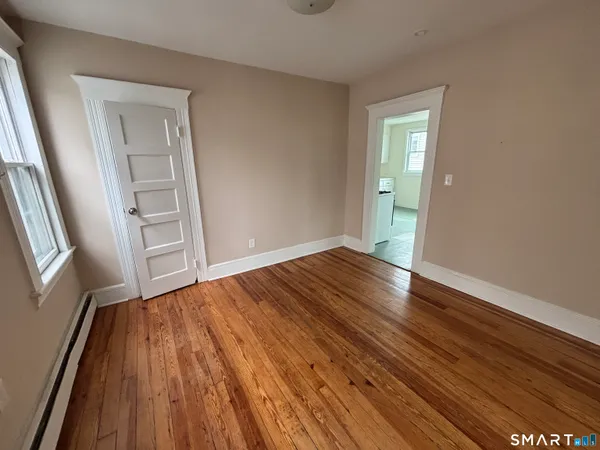 a view of an empty room with wooden floor and a window