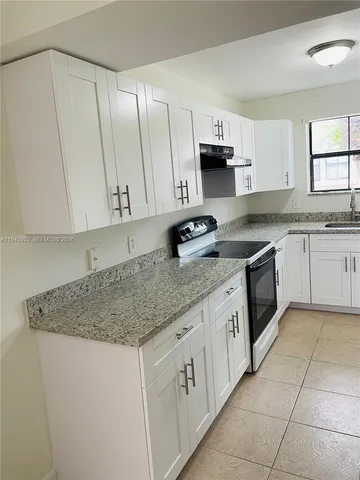 a kitchen with granite countertop a sink a stove and cabinets