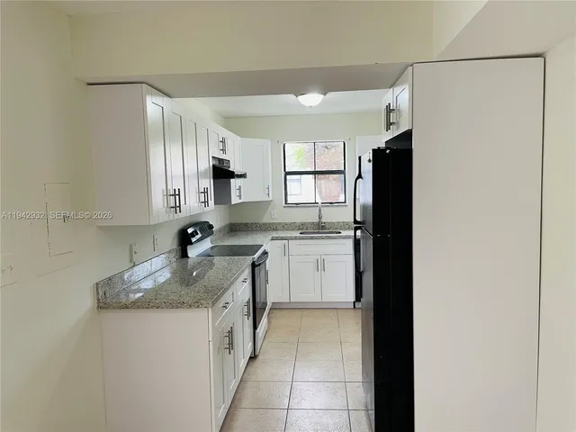 a kitchen with a refrigerator sink and cabinets