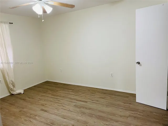 an empty room with wooden floor and fan