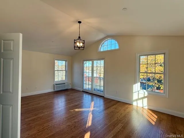 a view of an empty room with window and wooden floor