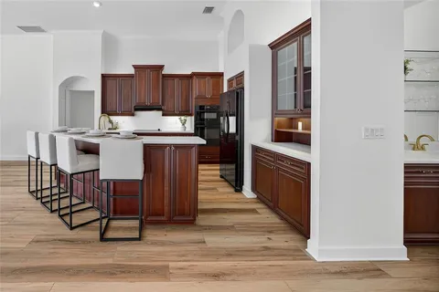 a kitchen with stainless steel appliances wooden floor and chairs
