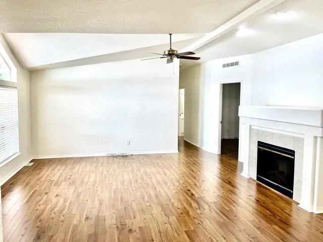 an empty room with wooden floor a fireplace and windows