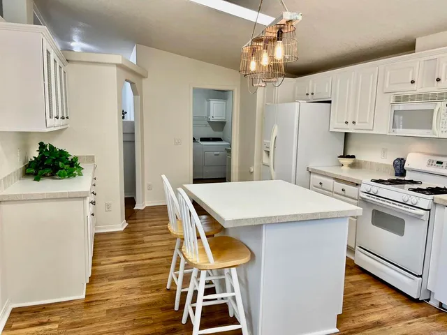 a kitchen with kitchen island a wooden floor and white appliances