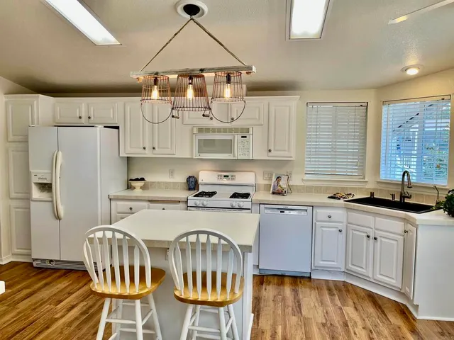 a kitchen with stainless steel appliances a dining table chairs sink and cabinets