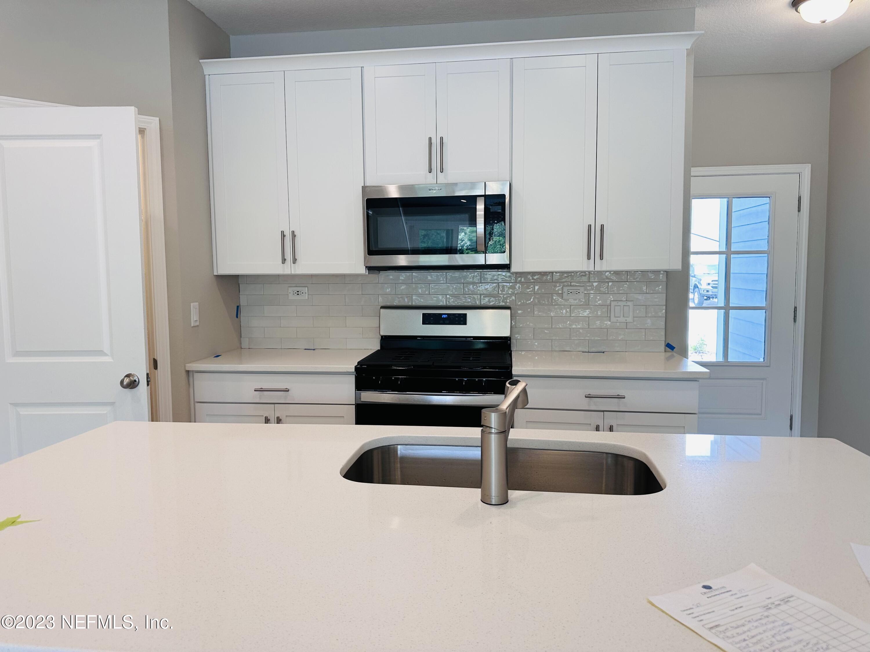 69 Thurnham Lane St. Augustine, FL 32092 - Photo 3 of 10 a kitchen with stainless steel appliances a stove a microwave and white cabinets