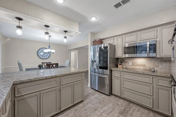 a kitchen with stainless steel appliances granite countertop a sink and a refrigerator