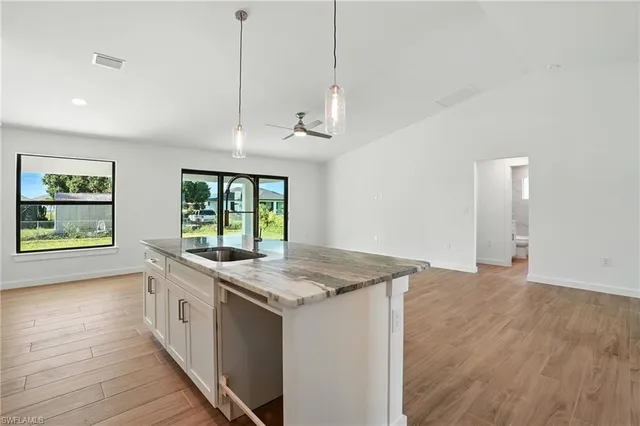 a kitchen with a stove a sink a window and wooden floor