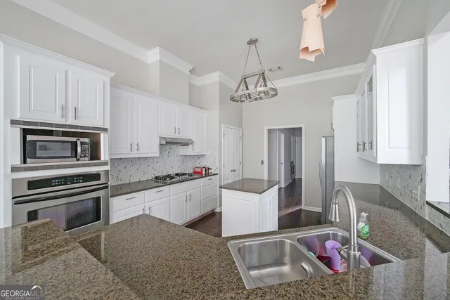 a kitchen that has a microwave a stove and white cabinets