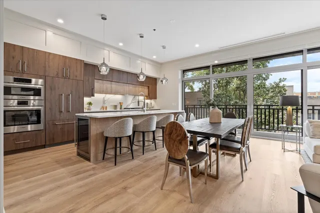 a dining hall with stainless steel appliances kitchen island granite countertop a dining table and chairs with wooden floor