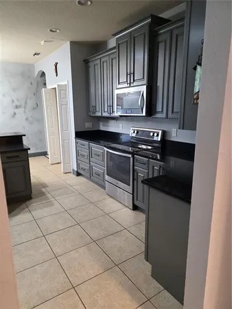 a kitchen with granite countertop a stove a sink and a refrigerator