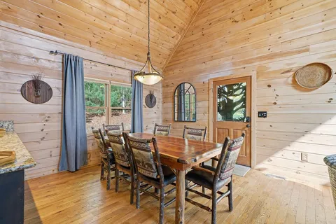a kitchen with stainless steel appliances granite countertop a stove a refrigerator a sink dishwasher a dining table and chairs with wooden floor