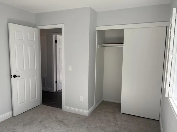 an empty room with wooden floor and closet area
