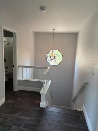 an empty room with wooden floor kitchen view and a living room