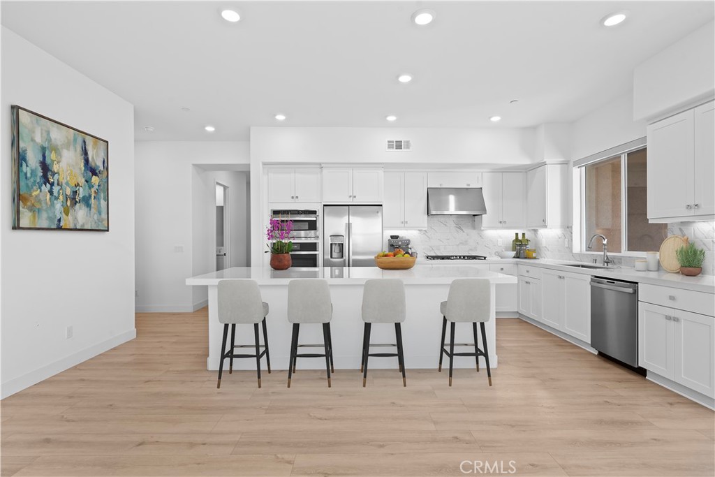 a kitchen with white cabinets and chairs