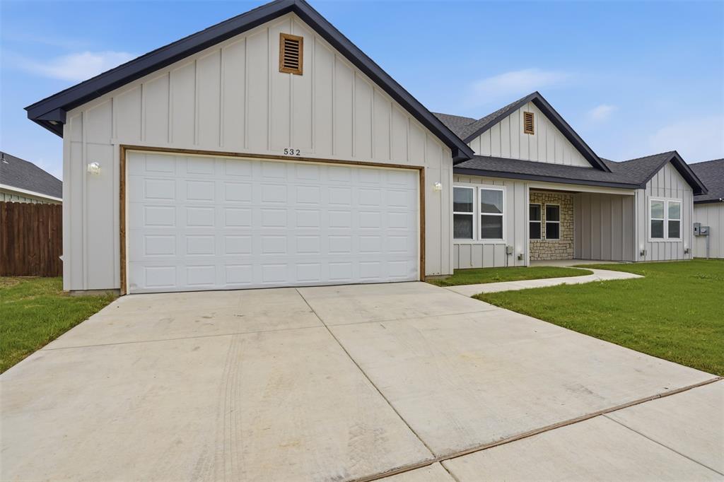 532 Highview Court Godley, TX 76044 - Photo 2 of 39 Modern farmhouse-style exterior featuring vertical board and batten siding, dark shingle roofing, a two-car garage, stone accent siding, and a paved walkway