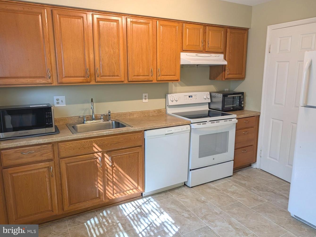 8582 Adamson Street Manassas, VA 20110 - Photo 10 of 24 a kitchen with white cabinets and white appliances