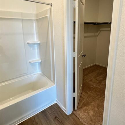340 The Bad Way Jarrell, TX 76537 - Photo 11 of 14 Bathroom featuring a walk in closet, shower / tub combination, and dark wood-type flooring