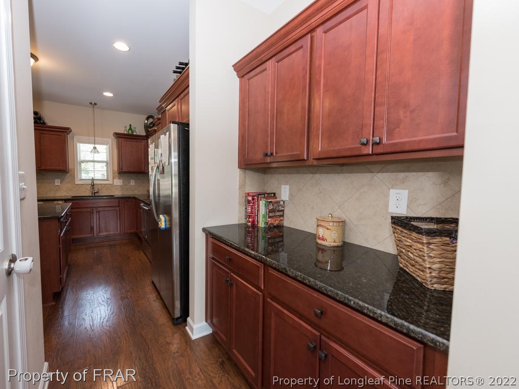717 St Johns Loop Raeford, NC 28376 - Photo 10 of 29 a kitchen with stainless steel appliances granite countertop a refrigerator a sink dishwasher and wooden cabinets with wooden floor