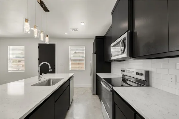 a kitchen with a sink dishwasher a stove top oven a refrigerator with wooden cabinets and floor
