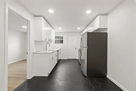 a kitchen with a refrigerator and white cabinets