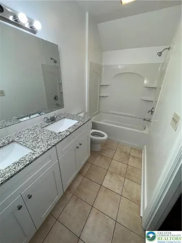 a bathroom with a granite countertop sink a toilet and a shower