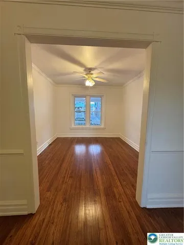 a view of an empty room with wooden floor and a window