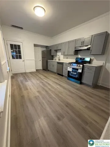 a living room with stainless steel appliances furniture and a kitchen view