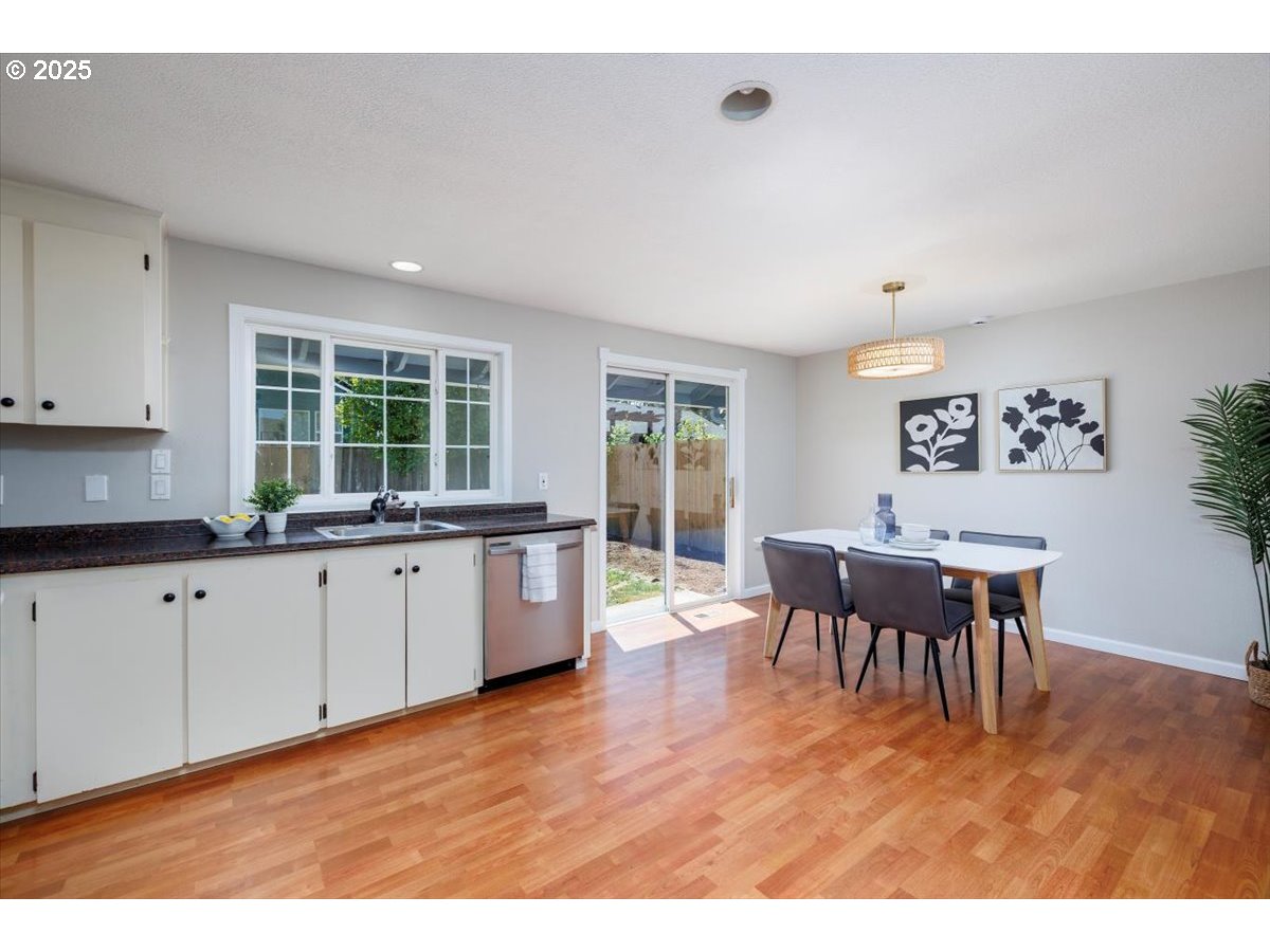 2610 Southwest 204th Avenue Beaverton, OR 97003 - Photo 12 of 37 a kitchen with stainless steel appliances granite countertop a stove a sink a dining table and chairs with wooden floor