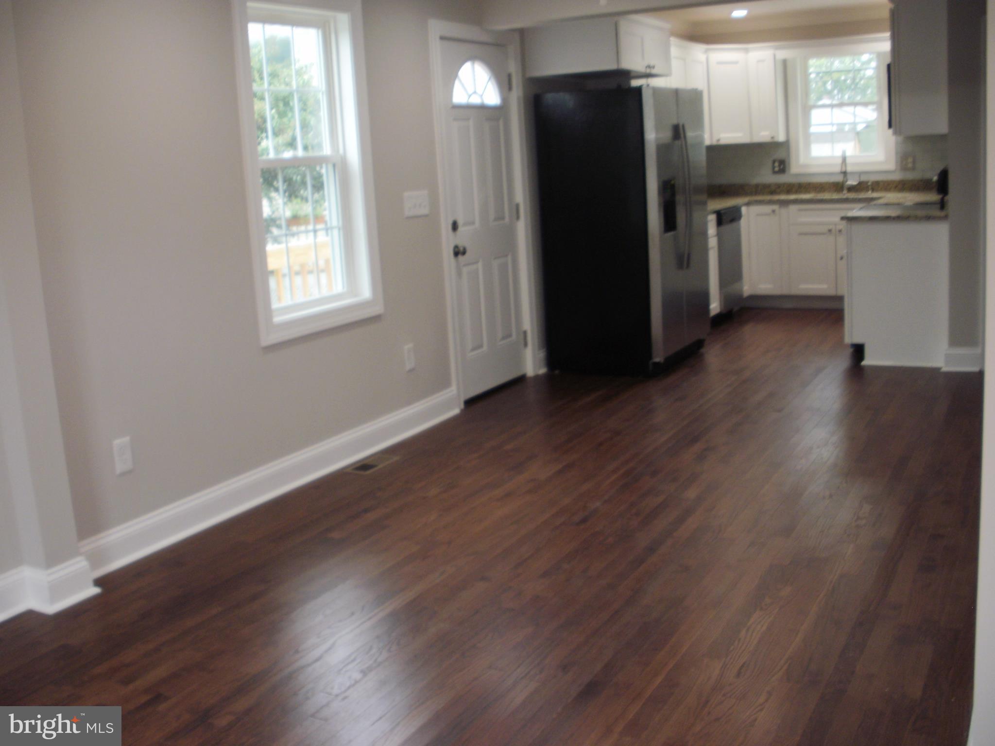 7350 Chesapeake Road Middle River, MD 21220 - Photo 2 of 21 an empty room with wooden floor and a kitchen