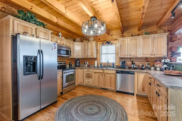 a kitchen with stainless steel appliances granite countertop a sink a stove a refrigerator cabinets and a dining table