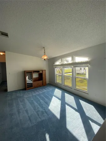 a view of an empty room with a window and a kitchen