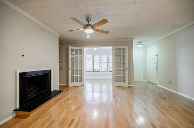 a view of an empty room with wooden floor and a fireplace