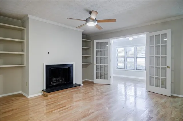 an empty room with wooden floor a fireplace and windows