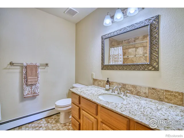 a bathroom with a granite countertop toilet a sink and mirror