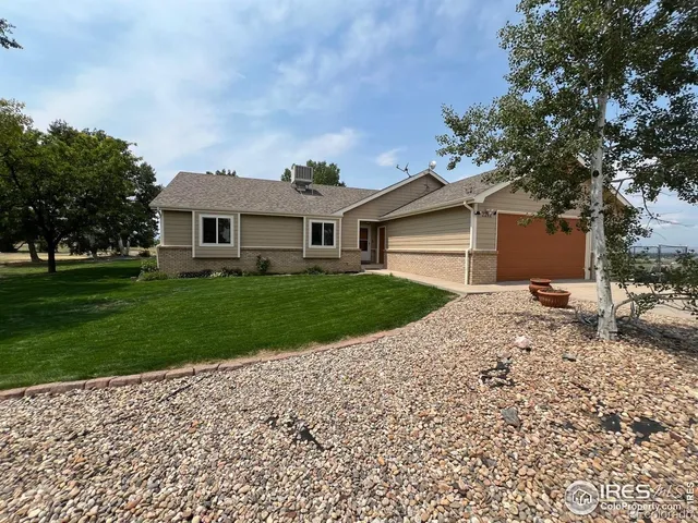 a front view of a house with a garden and trees