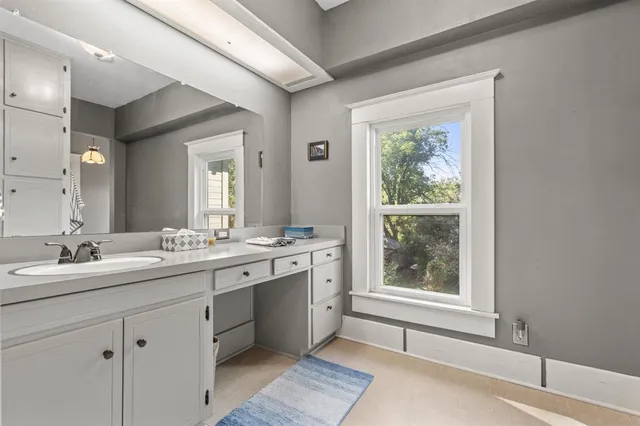 a bathroom with a double vanity sink and mirror with large window