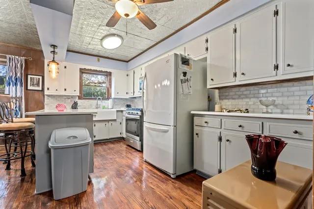a kitchen with a refrigerator a stove a sink dishwasher and white cabinets with wooden floor