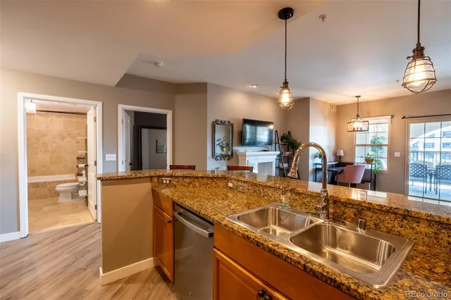 a kitchen island with granite countertop a sink cabinets and wooden floor