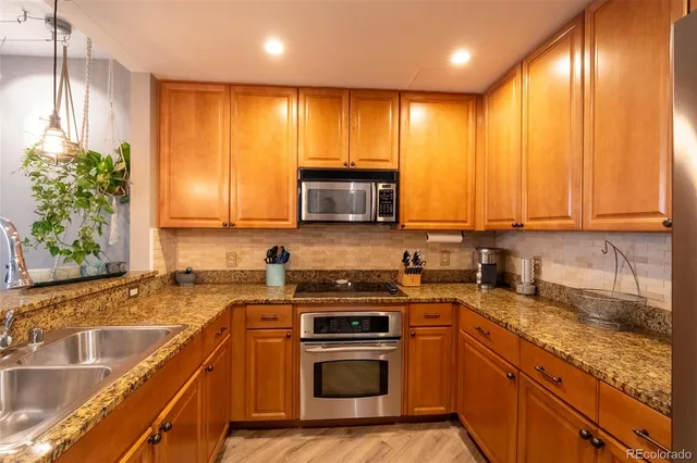 a kitchen with stainless steel appliances granite countertop wooden cabinets a stove top oven a sink and dishwasher