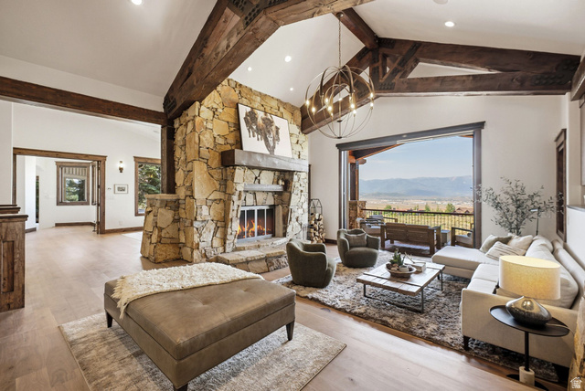 7885 North Rabbitbrush Court, Unit 13 Park City, UT 84098 - Photo 5 of 88 Spacious living area featuring exposed wood beams, a stone fireplace, wood-finish flooring, and a large sliding glass door opening to a mountain landscape