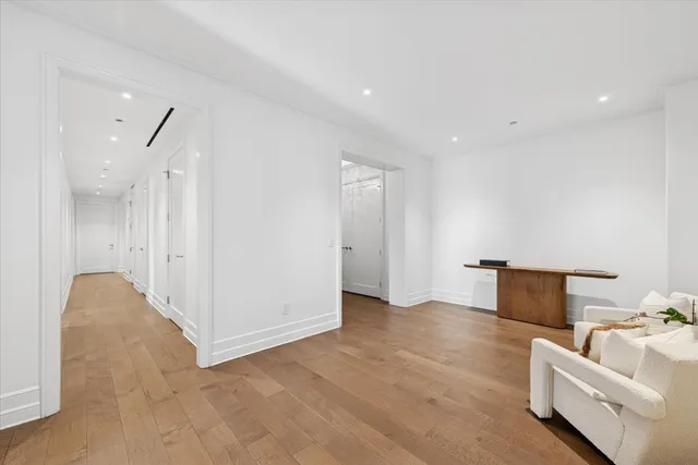 a view of an empty room with wooden floor and a bathroom