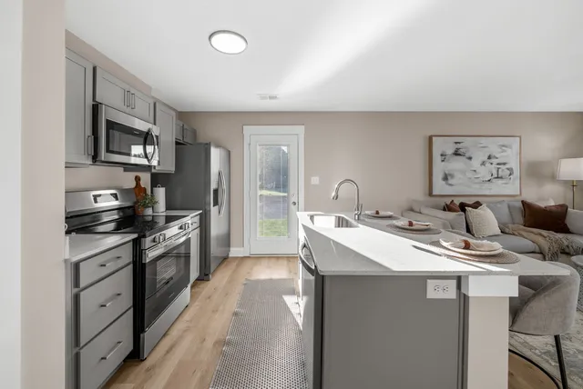 a kitchen with stainless steel appliances kitchen island granite countertop a sink stove and refrigerator