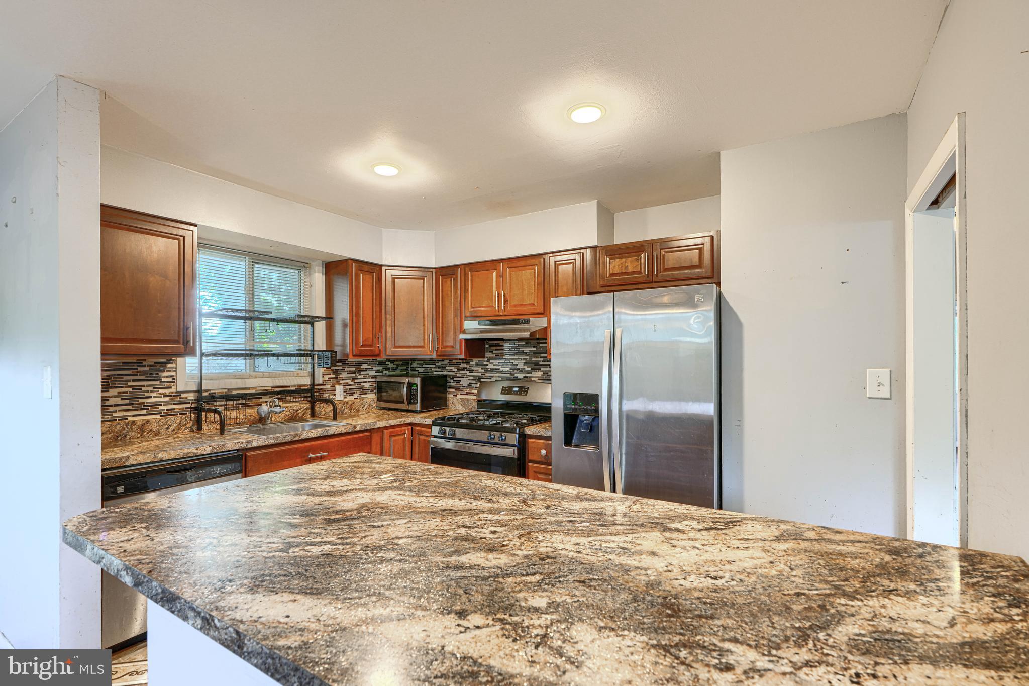 9706 Liberty Road Randallstown, MD 21133 - Photo 17 of 43 a kitchen with stainless steel appliances granite countertop a refrigerator a stove and a sink with wooden cabinets