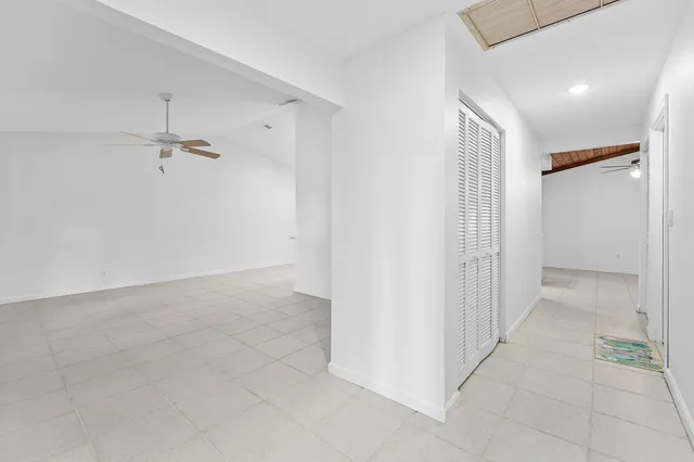 an empty room with windows and chandelier fan