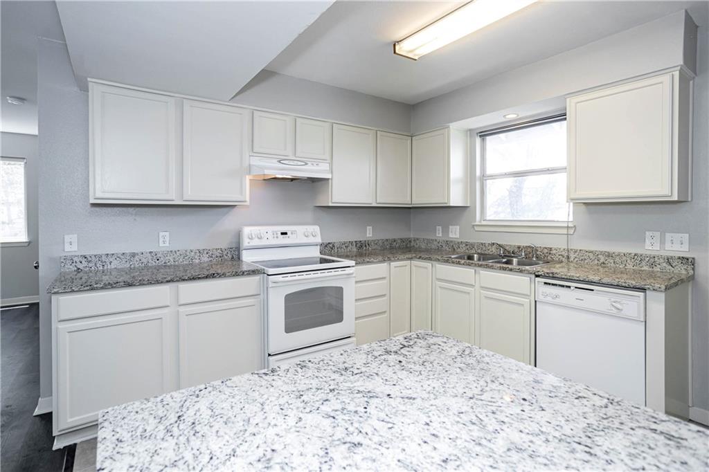 1326 Delano Street Austin, TX 78721 - Photo 12 of 23 Kitchen with white appliances, light stone counters, and white cabinets