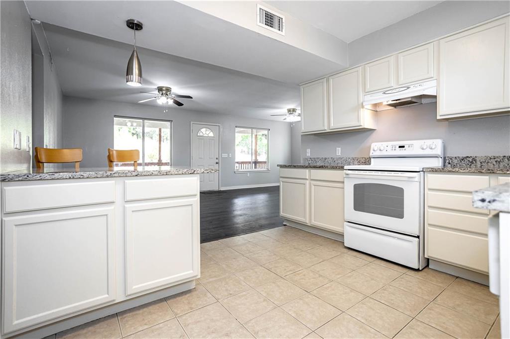 1326 Delano Street Austin, TX 78721 - Photo 13 of 23 Kitchen with electric stove, light stone counters, white cabinetry, ceiling fan, and hanging light fixtures