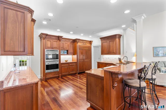 a large kitchen with stainless steel appliances granite countertop a large stove a sink dishwasher and a fireplace with wooden floor